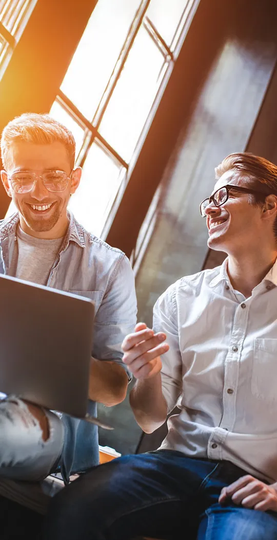 Zwei Männer sitzen auf einem Tisch und sind im Gespräch miteinander. 